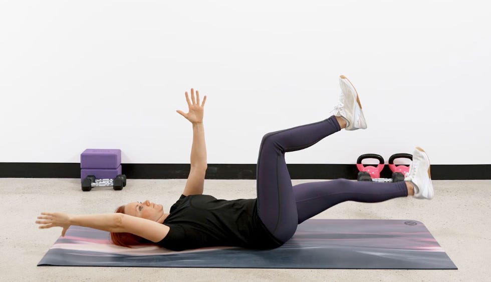 person performing an exercise on a mat with weights in the background