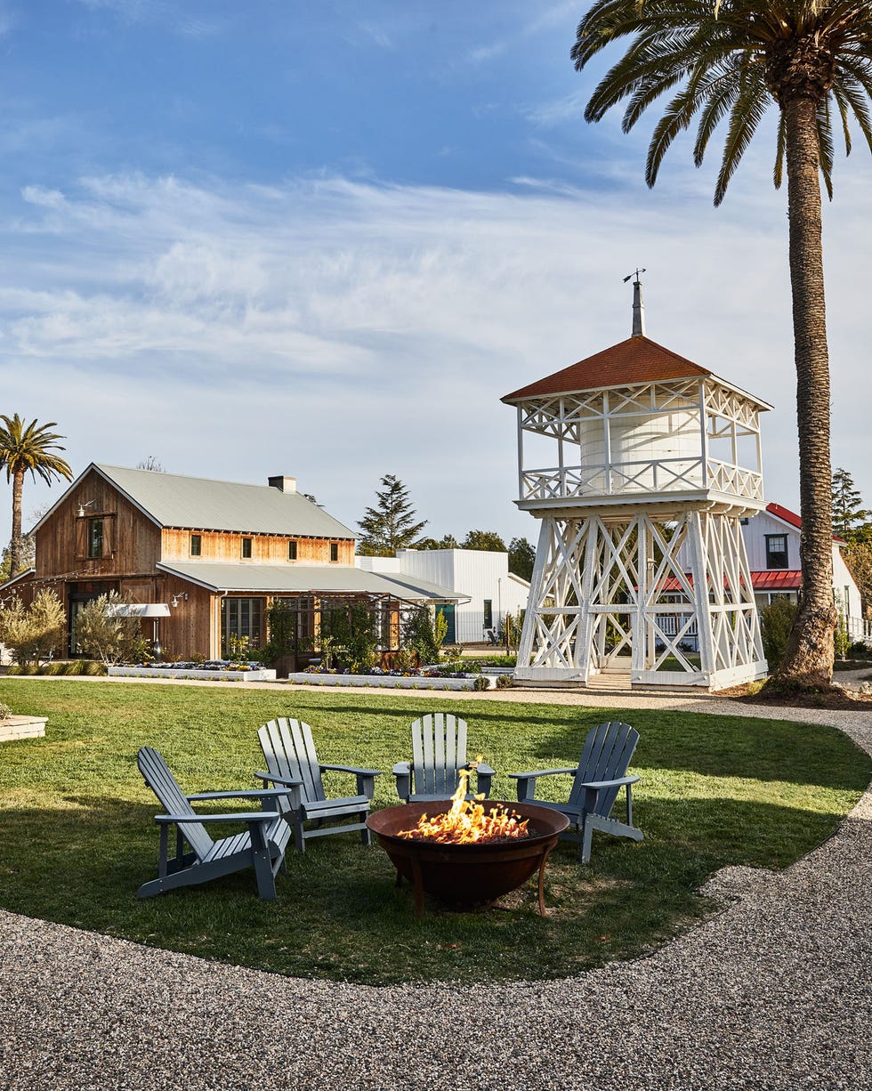 a fire pit with chairs and a gazebo in the background