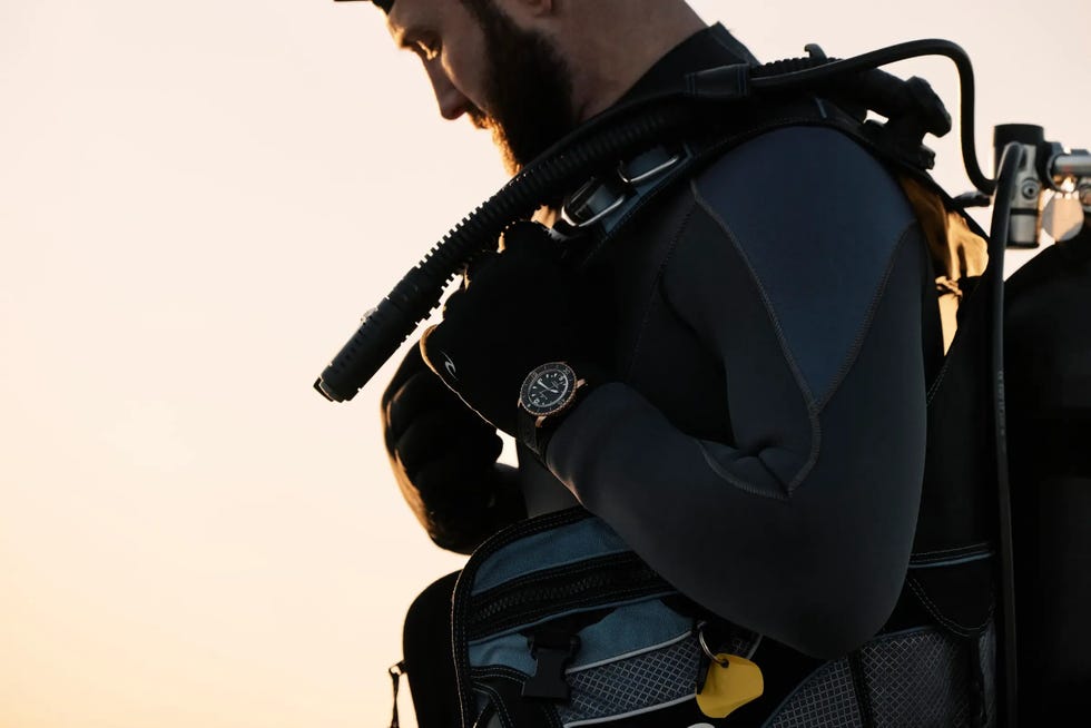 a person wearing a wetsuit and scuba gear preparing for a dive