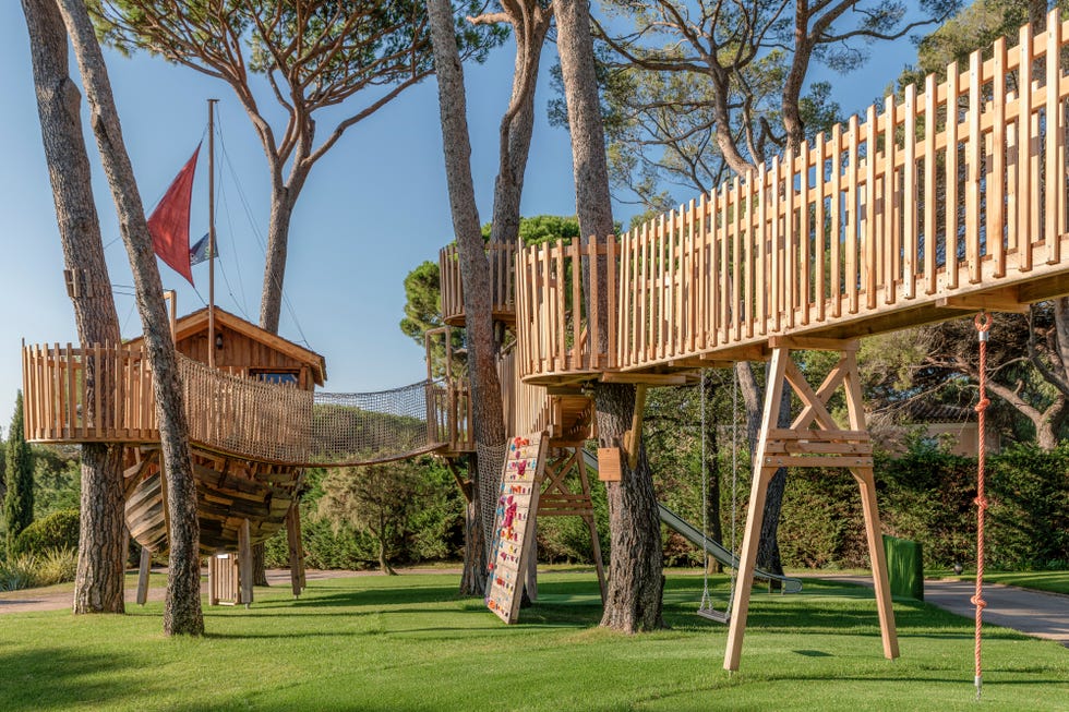 Treehouse and climbing structure in a green outdoor setting.