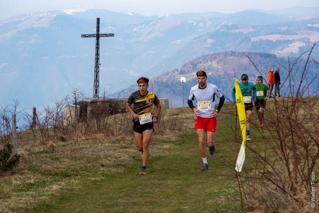 a group of people running on a trail with a tower in the background