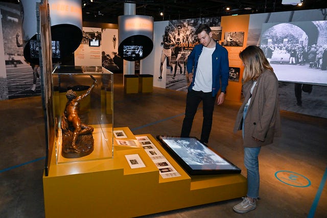 a man and woman standing next to a display of gold and silver objects