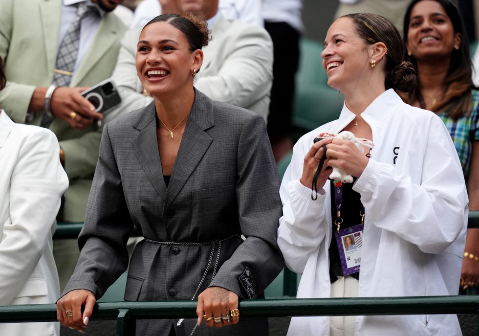 two women stand behind a green bar and smile
