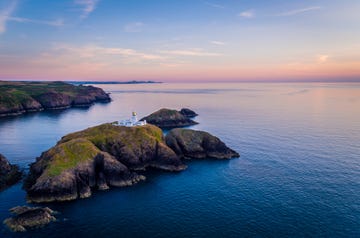 view of coastline and lighthouse at sunset