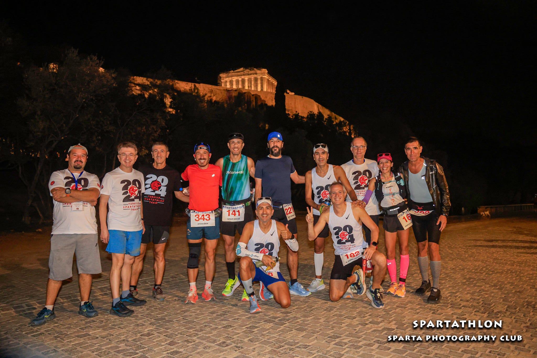 group of runners posing together at night with a historical monument in the background