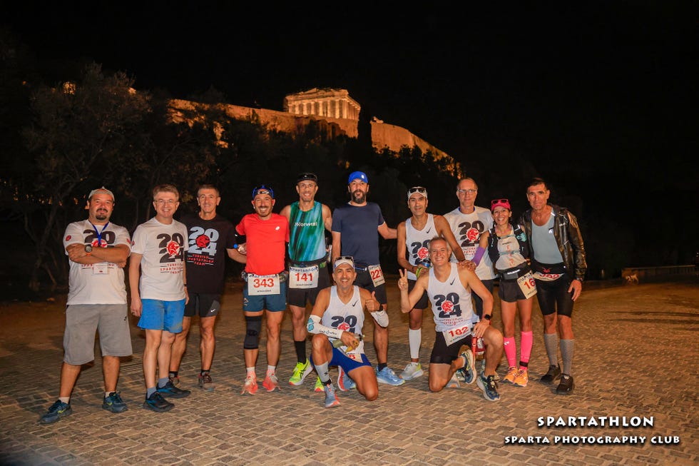 group of runners posing together at night with a historical monument in the background