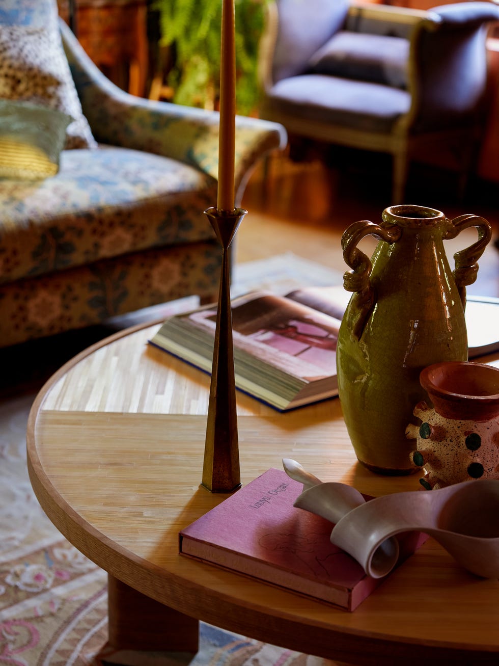 Coffee table arrangement with decorative items and seating in the background