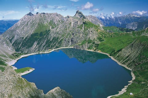 Een azuurblauw meer weerspiegelt de pieken van de omringende bergen in het wateroppervlak De Lnersee is met een kabelbaan te bereiken De hoogste top in de omgeving is de bijna 3000 meter hoge Schesaplana die avontuurlijke wandelaars kunnen beklimmen