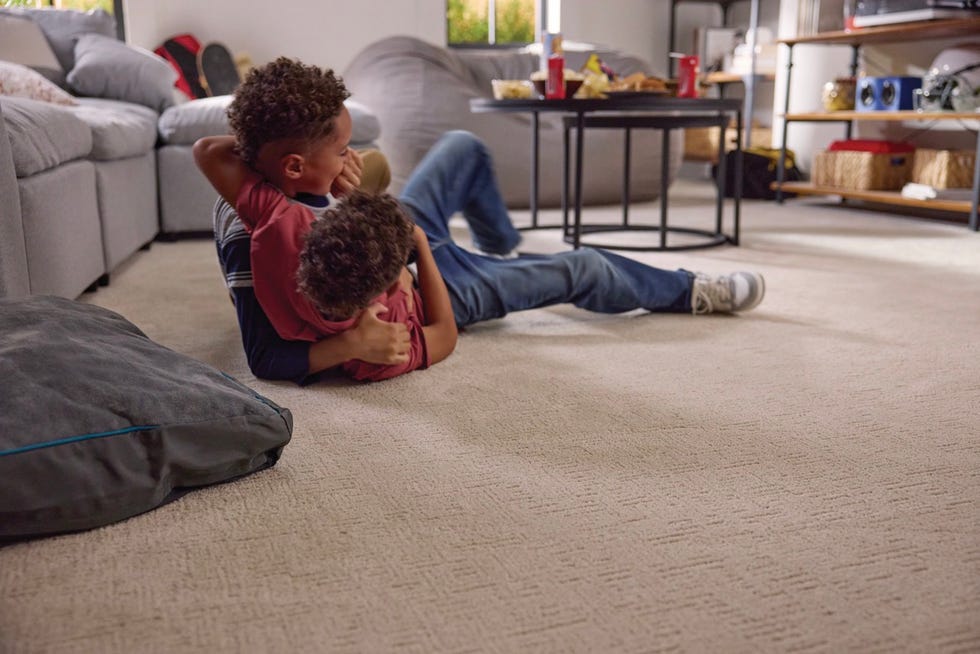 two children play together on a carpeted floor indoors