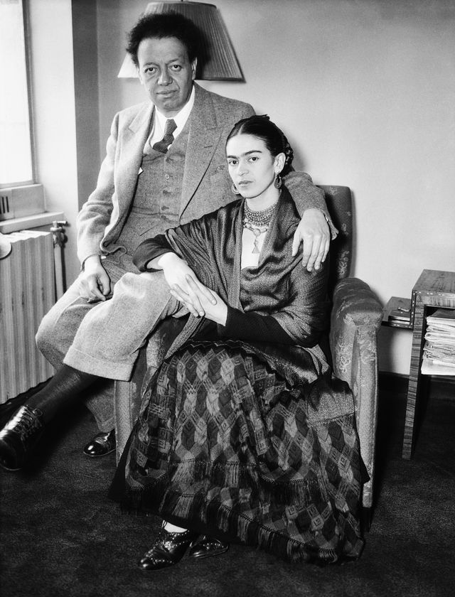 Diego Rivera perches amicably on Frida Kahlo’s chair at their home.