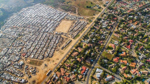 Een buurt met groene gazons en helderblauwe zwembaden grenst aan een township met huisjes van golfplaat in Boubosrand een township in het noordwesten van Johannesburg ZuidAfrika