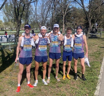 a group of people wearing numbers and running on a path