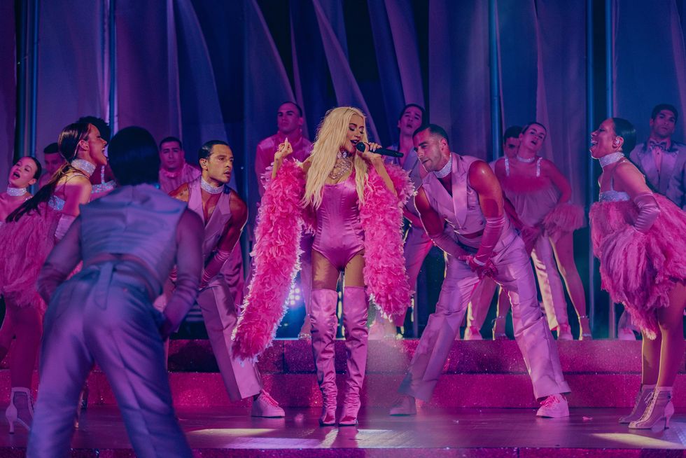 christina aguilera performing on stage with a pink feather boa