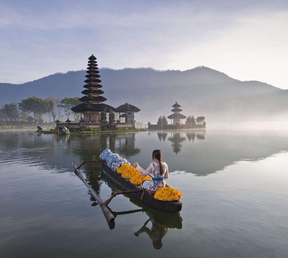Bali, woman rowing boat infront of Ulun Danu Bratan temple