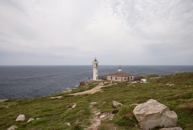 a lighthouse on a hill by the water