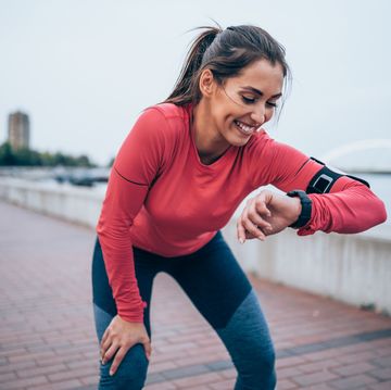 een vrouw kijkt op haar horloge tijdens het hardlopen