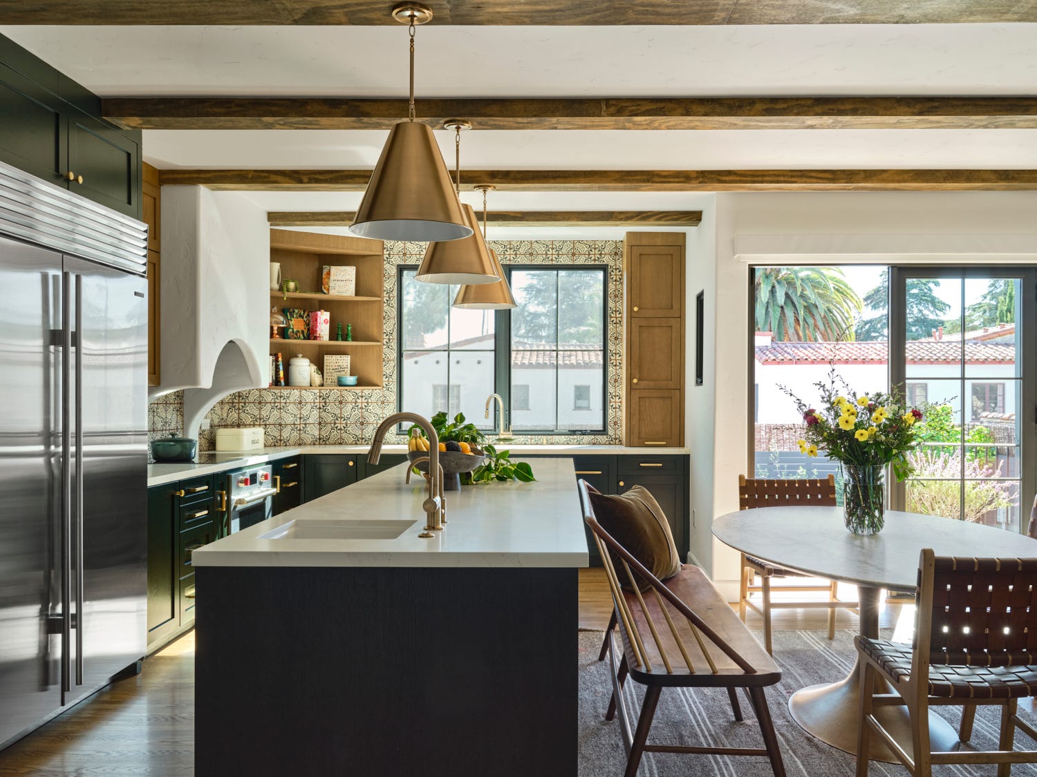 a spacious kitchen featuring a central island with a white countertop, surrounded by a sleek cabinetry in dark shades