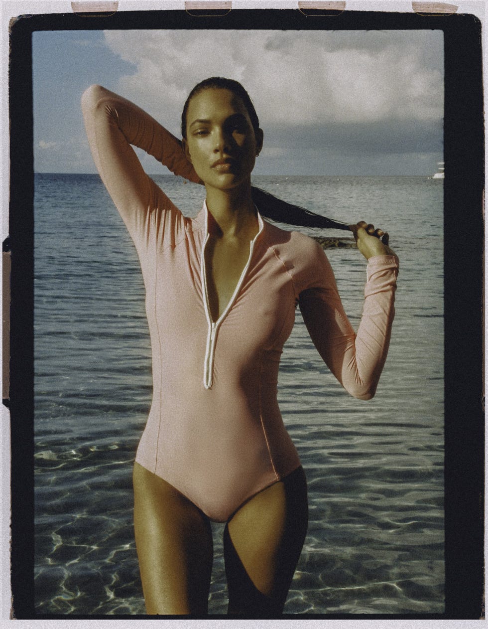 person in a pink swim suit standing in shallow water