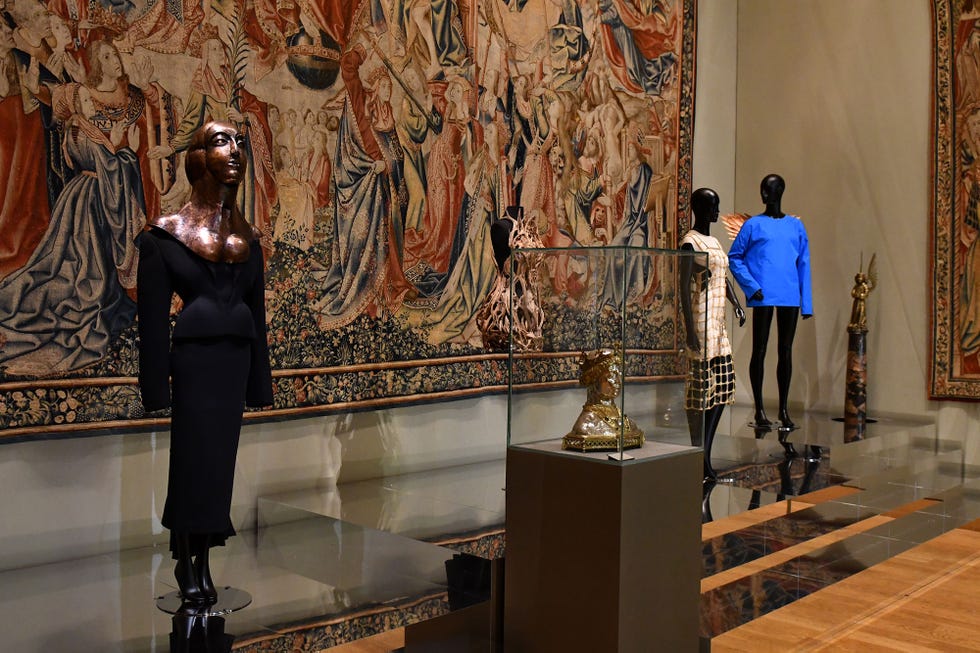 Exhibition featuring contemporary fashion displayed alongside historical tapestries.