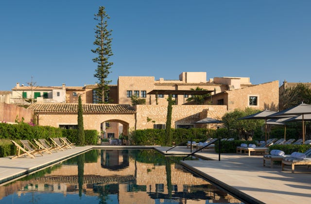 Luxury villa with a swimming pool and loungers set in a garden.