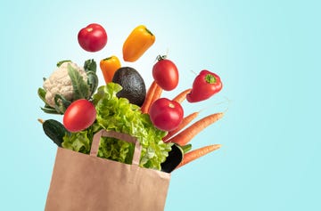 grocery bag of fresh vegetables on blue summer sky background