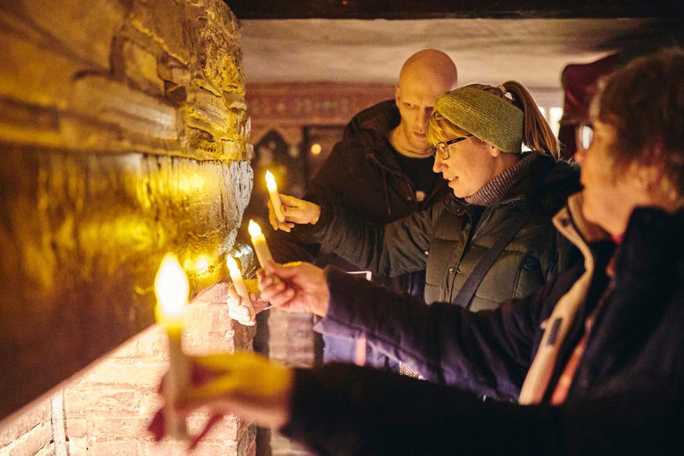 individuals holding candles in a dimly lit setting