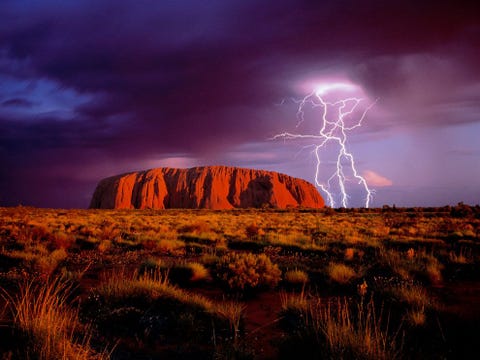 Bliksem boven Ayers Rock de bekende rots van rood zandsteen die toeristen naar het binnenland van Australi lokt De monoliet die door de Aboriginals de oorspronkelijke bewoners van het continent Uluru wordt genoemd ligt in het UluruKata Tjuta National Park
