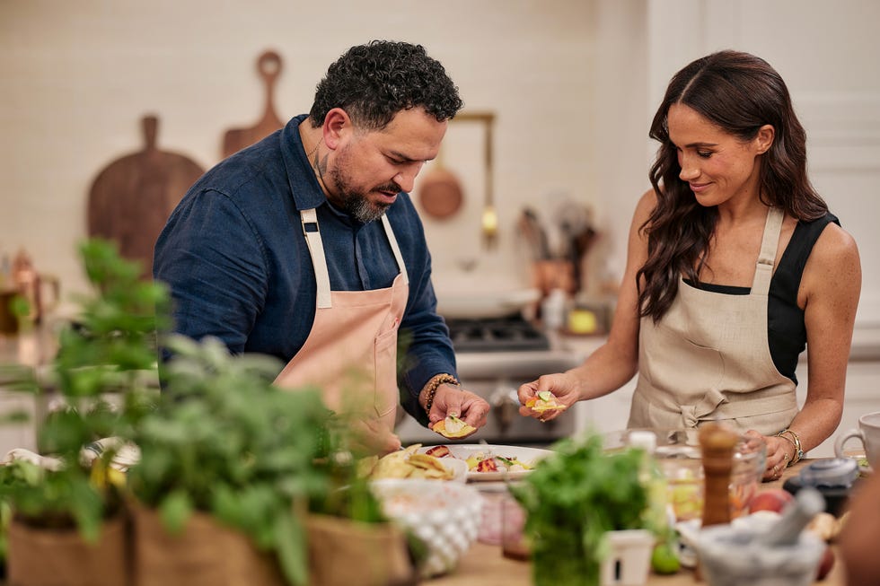 Two individuals engaged in food preparation in a kitchen setting.