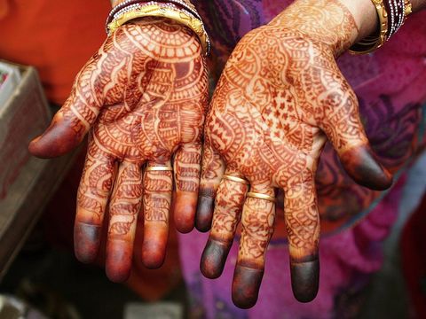 De handen van een vrouw in Jaipur zijn bedekt met mehndipatronen die met henna zijn geschilderd In de afgelopen jaren zijn deze kantachtige patronen steeds populairder geworden maar ze maken deel uit van een vijfduizend jaar oude traditie van decoraties die bedoeld zijn om boze geesten af te weren of een gevoel van geluk uit te drukken