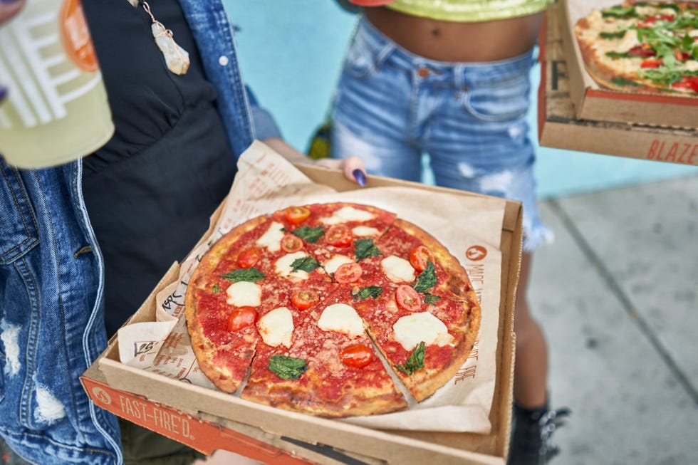 two people holding boxes of pizza