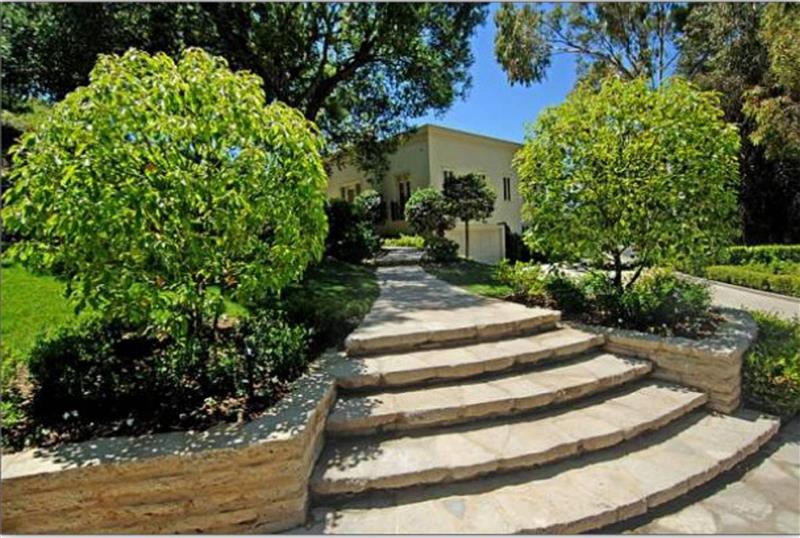 Pathway leading to a modern house surrounded by greenery.