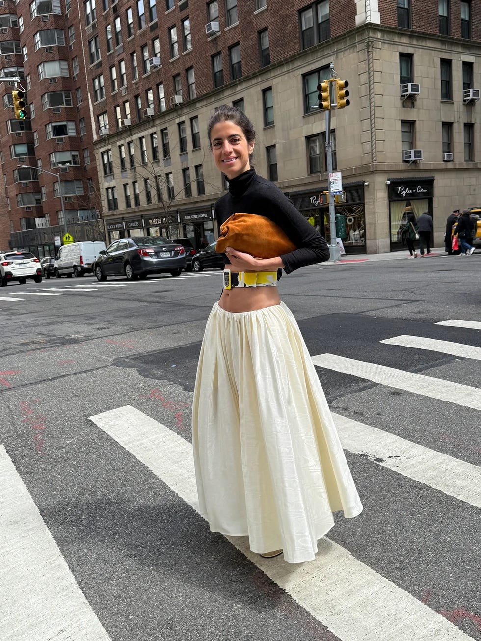 a person crossing the street in a city setting wearing a fashionable outfit