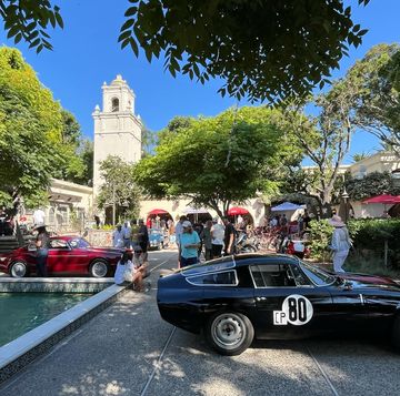 a group of cars parked by a fountain and people walking around