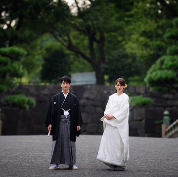 橋の上で白無垢と紋付き袴を着て立つ男女