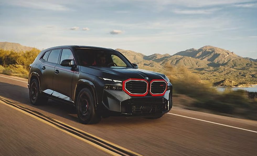 a black bmw suv driving on a scenic road with mountains in the background