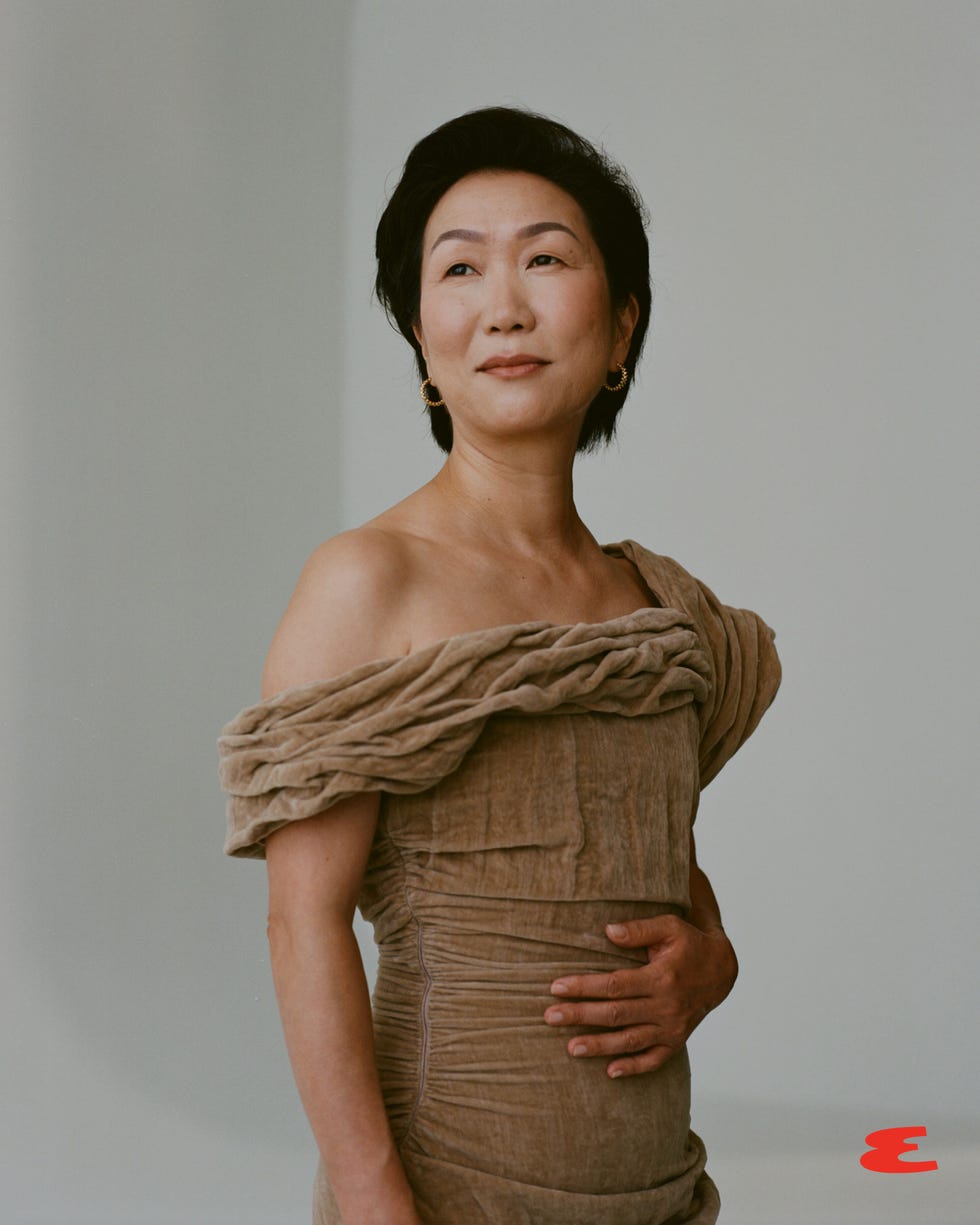 a person wearing an elegant offshoulder dress standing in a neutral setting