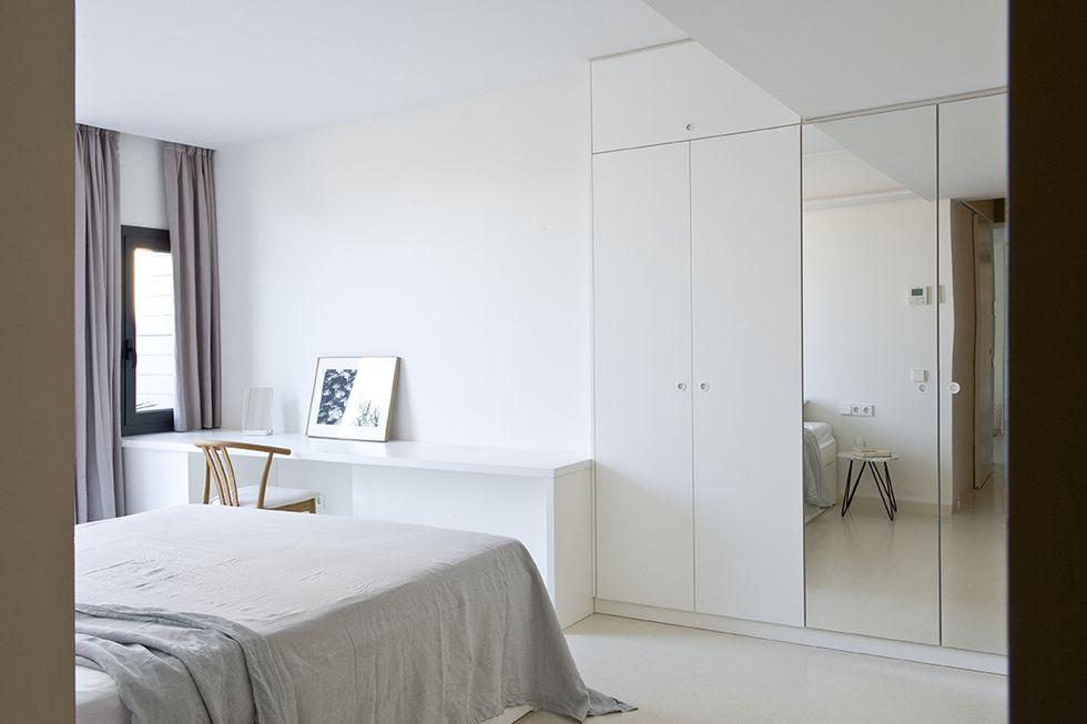 un dormitorio en blanco con armarios de espejo