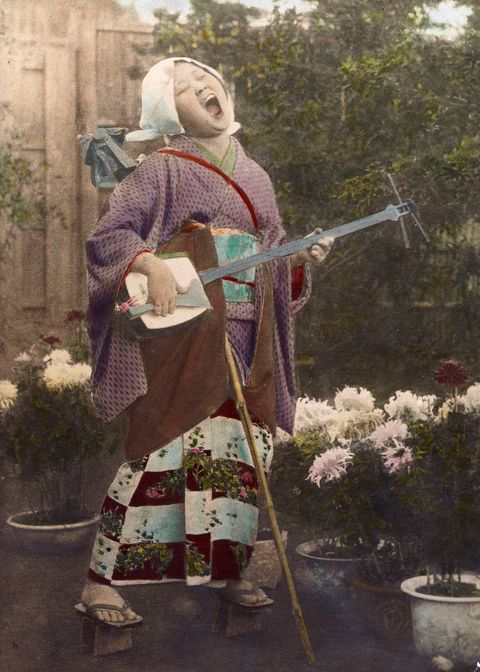 Een Japanse vrouw zingt terwijl ze op een samisen speelt een traditioneel driesnarig instrument