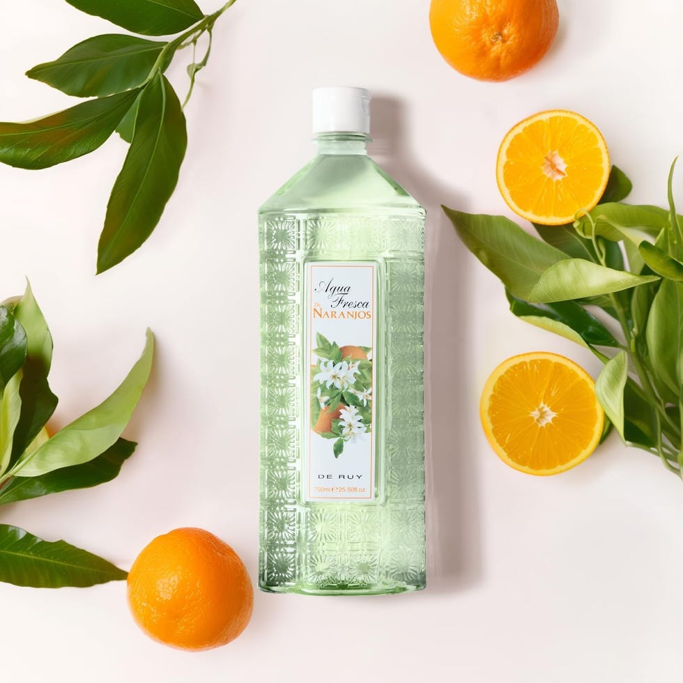 bottled fragrance surrounded by oranges and green leaves