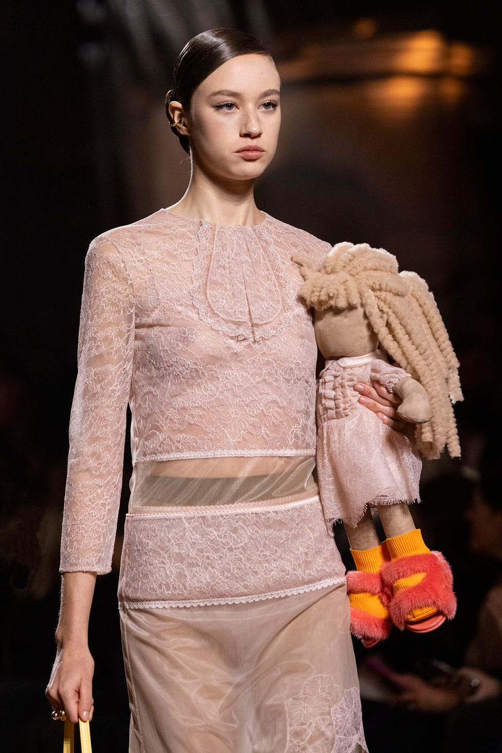 a model showcases a lace outfit while holding a plush toy