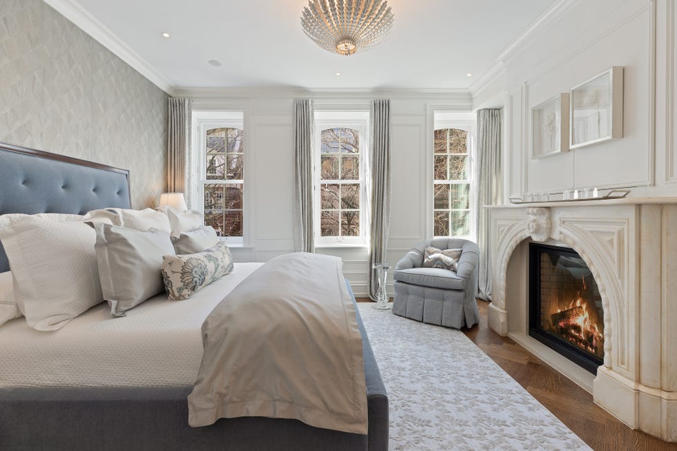 Cozy and elegant bedroom featuring a fireplace and large windows.