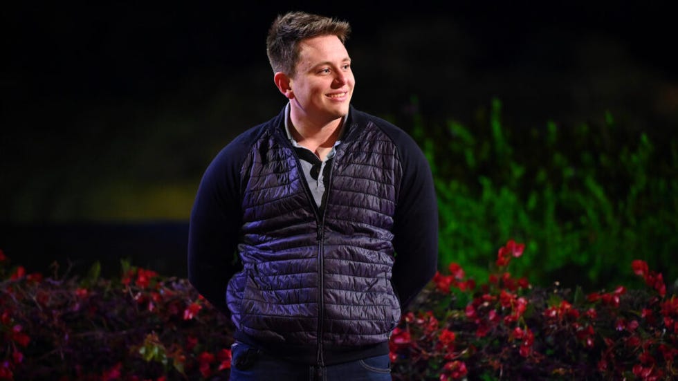 Man standing outdoors at night with a floral background.