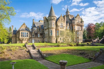 a large stone building with a lawn and a fountain in front of it