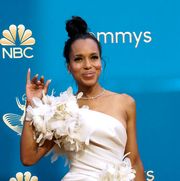 kerry washington in a white dress with floral appliques waving her right hand at the 74th primetime emmys arrivals in front of blue nbc emmys graphic