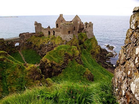 Het Dunluce kasteel Je ziet meteen waarom het kasteel van Dunluce in NoordIerland zon goed te verdedigen vesting was het staat bovenop een hoge rotsachtige punt die uitsteekt boven zee en is alleen per brug vroeger een ophaalbrug over een ravijn bereikbaar Het stamt uit de 13e eeuw en was een tijd lang de residentie van Clan MacDonnell Loop door de gebogen poort met wachttoren naar de sfeervolle binnenplaats waar je de rune kunt bekijken en genieten van het verre uitzicht over de kliffen van de Anthrim kustlijn La Girona een schip van de Spaanse armada leed schipbreuk in 1588 hier vlakbij en sommige van de teruggevonden kanonnen schijnen op het kasteel terechtgekomen te zijn De graaf van Antrim bouwde een luxe woonverblijf binnen de muren maar de keuken schijnt in zee gestort te zijn in 1639 met personeel en al Verarmd na de Battle of the Boyne in 1690 toen hij de verliezende kant steunde verliet de graaf Dunluce en verhuisde hij naar een van zijn andere huizen Het kasteel is nu het hoogtepunt van de 53 kilometer lange Causeway Coast Way wandelroute