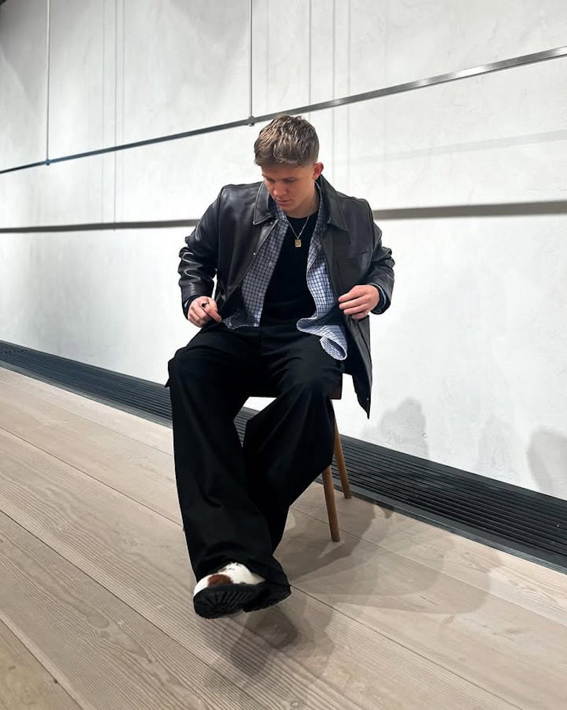 individual seated on a wooden chair in a contemporary indoor space