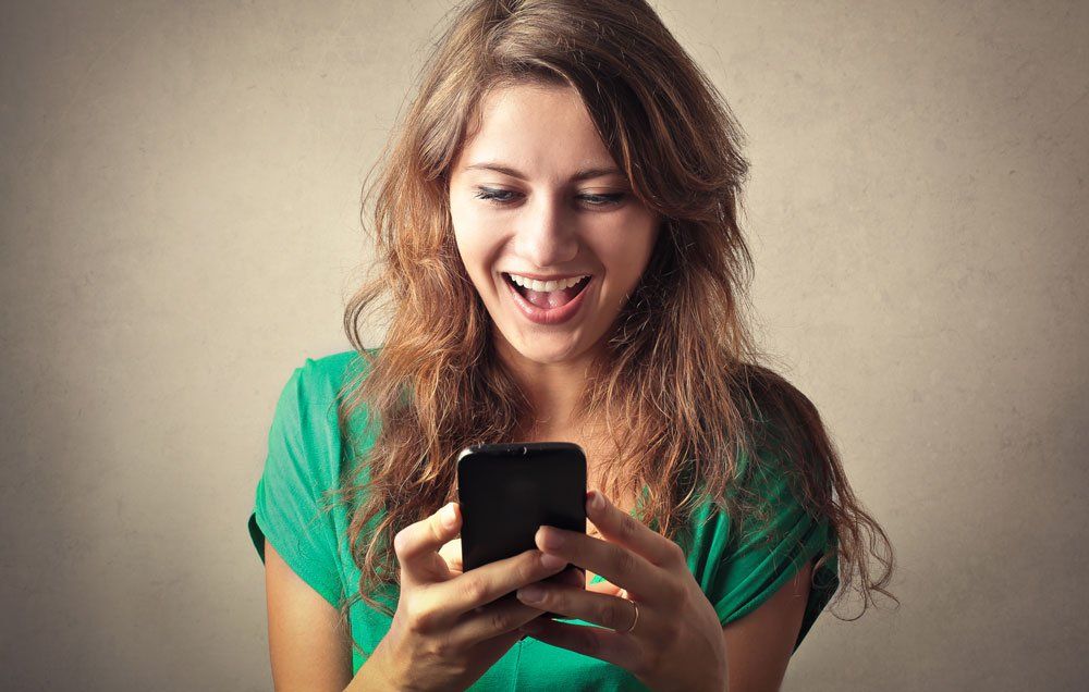 A woman happily looking at her phone.