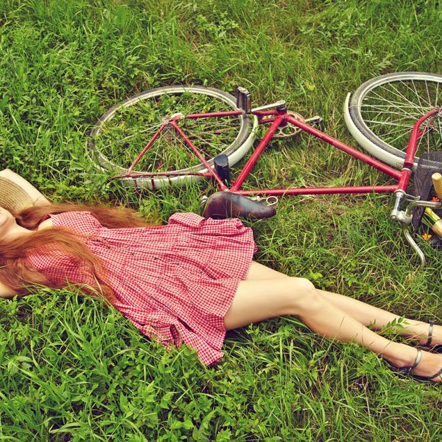 a woman laying in the grass next to her bike.