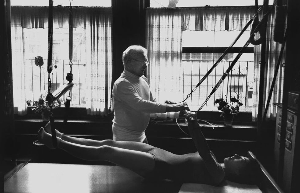 Joesph Joe Pilates in zijn studio in New York met een klant  onderdeel van een reeks fotos gemaakt door fotojournalist IC Rapoport in 1961 toen Pilates 78 jaar oud was en nog steeds een fervent student van zijn eigen methode