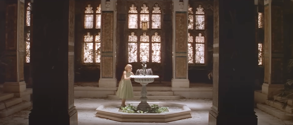 Interior of an abandoned building featuring a fountain and ornate windows.